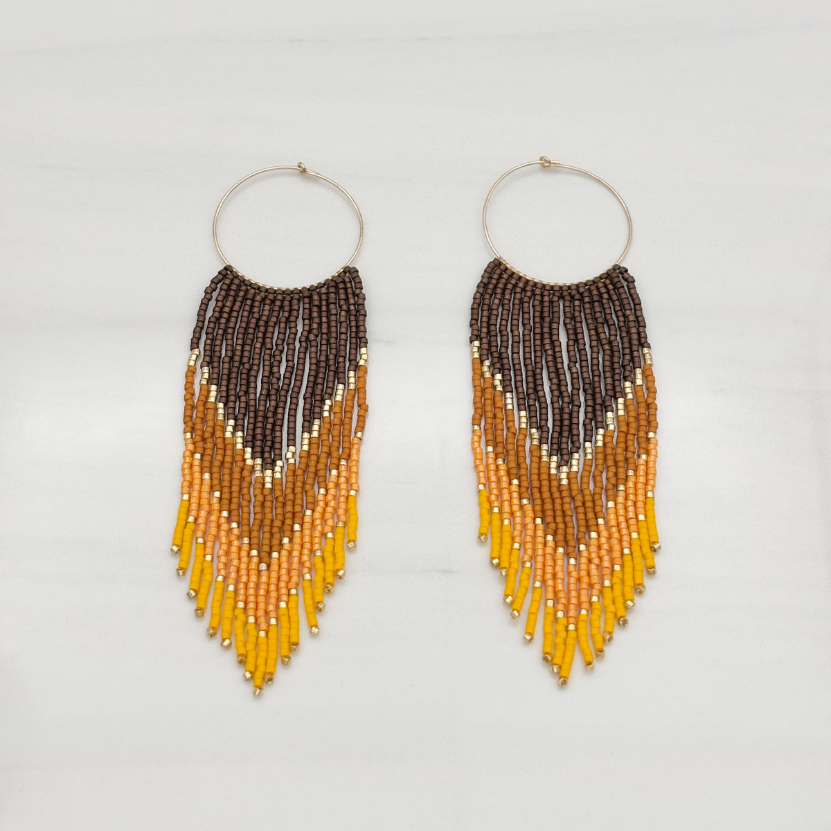 A pair of gold-filled frame bead fringe earrings with a geometric pattern, featuring colors brown, yellow, and orange.